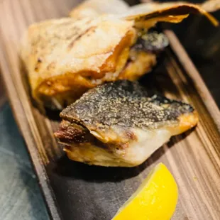 a piece of fish on a plate with a lemon wedge