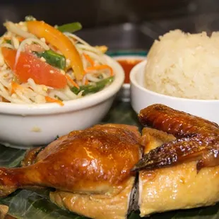 Thai BBQ chicken with sides of papaya salad and sticky rice