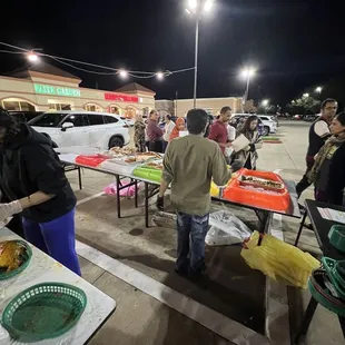 a group of people standing around a table of food