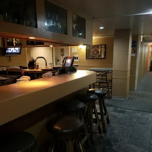The bar with bar stools and two tables in back.