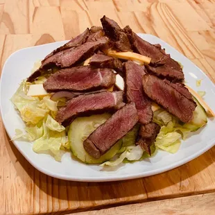 a steak salad on a white plate