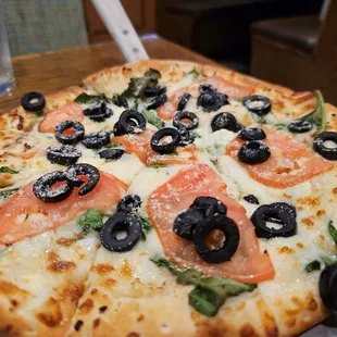 a pizza with tomatoes and black olives
