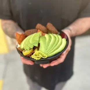 a man holding a bowl of avocado