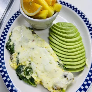 an omelet with spinach, avocado, and orange slices