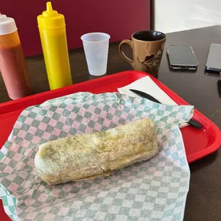 Breakfast burrito and all my stuff on the table.