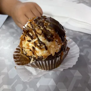 a hand reaching for a cupcake