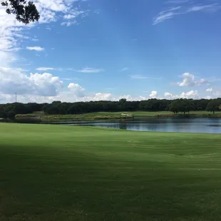 a green with a lake in the background