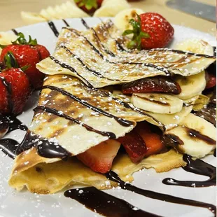 a plate of food with strawberries and chocolate sauce