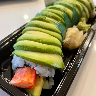 a sushi roll with cucumber, crab, and avocado