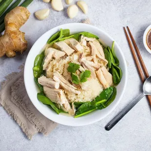 a bowl of chicken rice with a side of vegetables