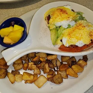 a plate of eggs benedict and potatoes