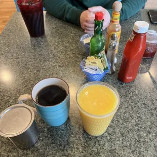 a person sitting at a table with drinks and condiments