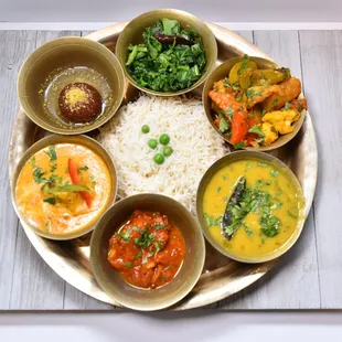 Lunch platter with rice, vegetables, greens, lentils, protein of choice, sweets