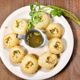 Pani puri (Round, hollow puri, crisp and filled with a mixture of flavored water, tamarind chutney, chaat masala, potato, chickpeas)