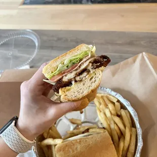 a person holding a sandwich and french fries