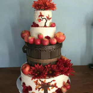 a three tiered cake with apples and flowers