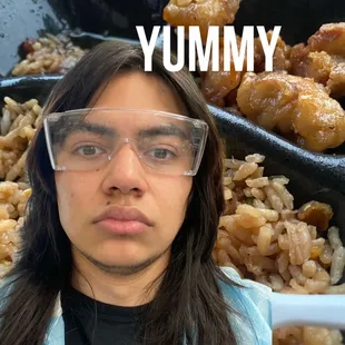 a man with long hair and glasses in front of a tray of food