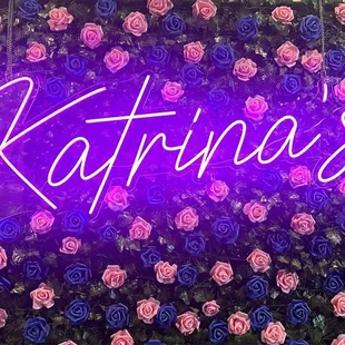 a neon sign surrounded by roses