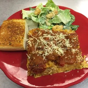 Homemade spaghetti pie with Caesar salad and garlic bread.