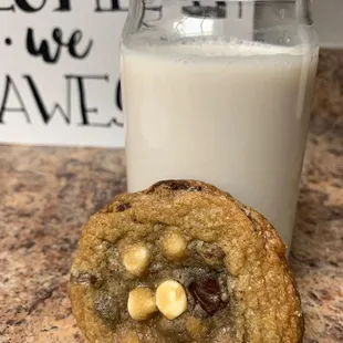 a chocolate chip cookie next to a glass of milk