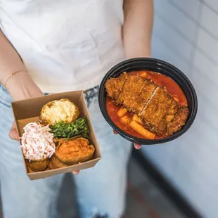 a woman holding a box of food