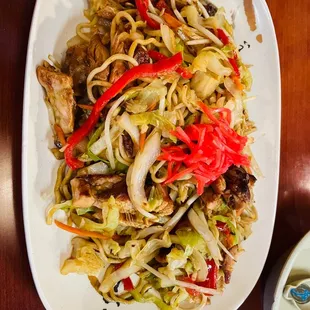 a plate of stir fried noodles with meat and vegetables