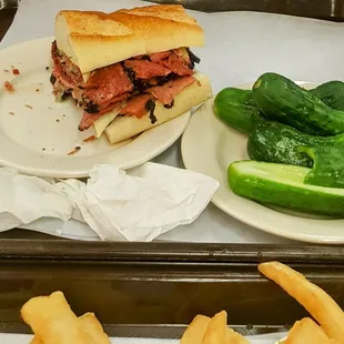 This is half of a Pastrami Sandwich and pickles.