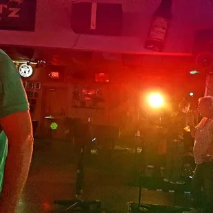 a man in a green shirt standing in a bar