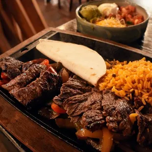 Steak Fajitas: made with onion &amp; peppers. Served with Mexican rice, tortillas, cheese, guacamole, sour cream, and pico de gallo ($29).