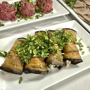 a plate of eggplant rolls and a plate of meatballs