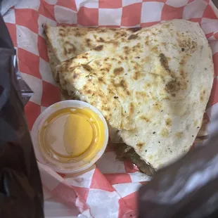 Our to-go order. Chicken &amp; cheese quesadilla with cheese sauce on the side.