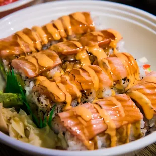 a bowl of sushi with sauce on top