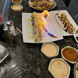 Flaming sushi  and a variety of sauces.