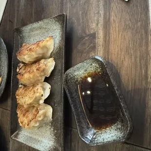 a plate of dumplings and a bowl of dipping sauce