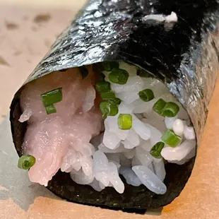 a sushi roll with rice and green onions