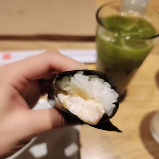 a hand holding a piece of sushi