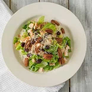 Fresh romaine lettuce topped with Cajun seasoned chicken, tomatoes, croutons, cranberries, pecans and cheese with a side of salad dressing.
