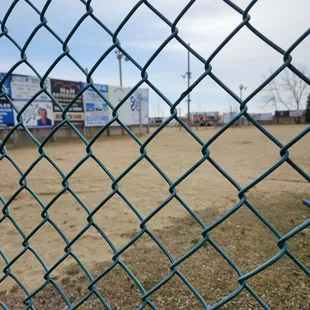a baseball field through a chain link fence