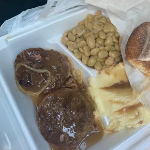 Hamburger steak with gravy and mashed potatoes with Lima beans.