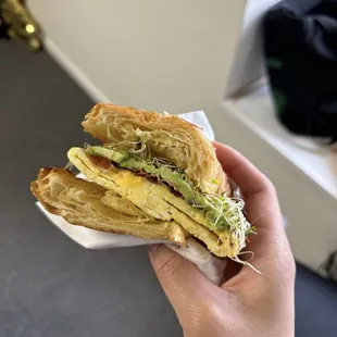 Breakfast croissant with bacon, add avocado and sprouts
