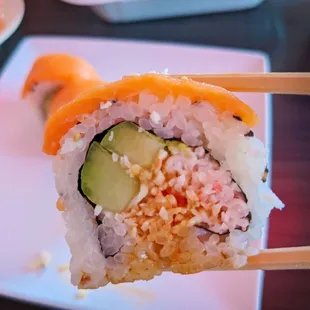 a closeup of a piece of sushi on a plate with chopsticks