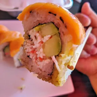 a hand holding a piece of sushi