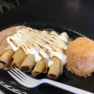 Potato flautas, entomatada style with tomato sauce, sour cream, and cheese. Served with rice and beans.