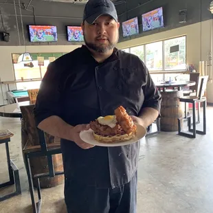 Chef presenting his specialty dish of chicken and waffles with fried cod add on