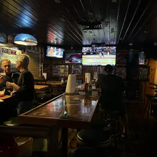 people sitting at a bar watching tvs