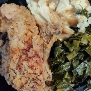 Two pork chops, collard greens and mashed potatoes with gravy.
