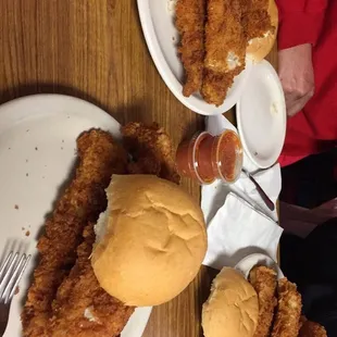 two plates of fried chicken and a sandwich