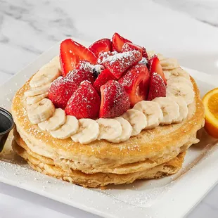 a stack of pancakes with strawberries and bananas