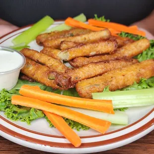 a plate of chicken strips with carrots and celery