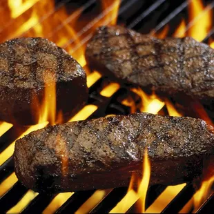 steaks cooking on a grill